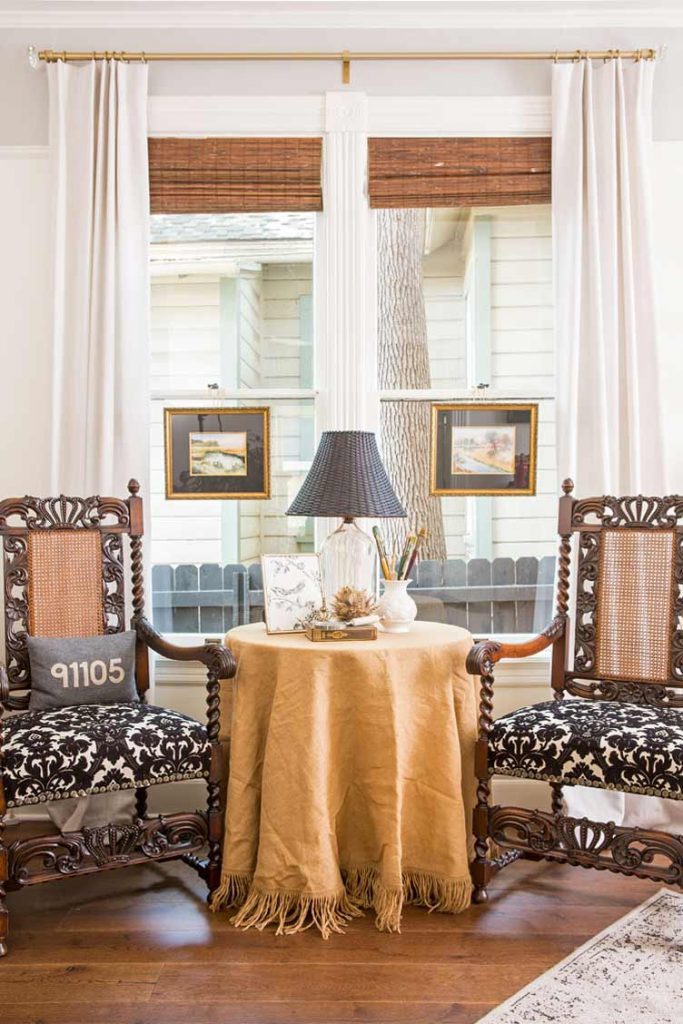 two reupholstered victorian chairs separated by a table with lamp and shade with architectural salvage decor