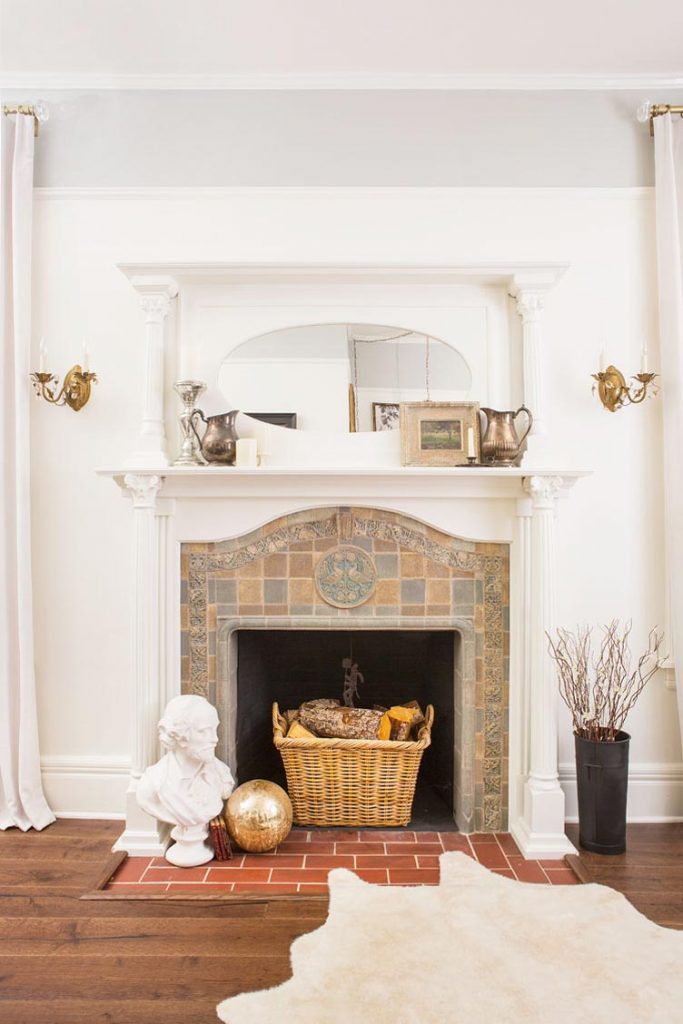 tiled fireplace embedded into wall surrounded by white mantel and red brick floor