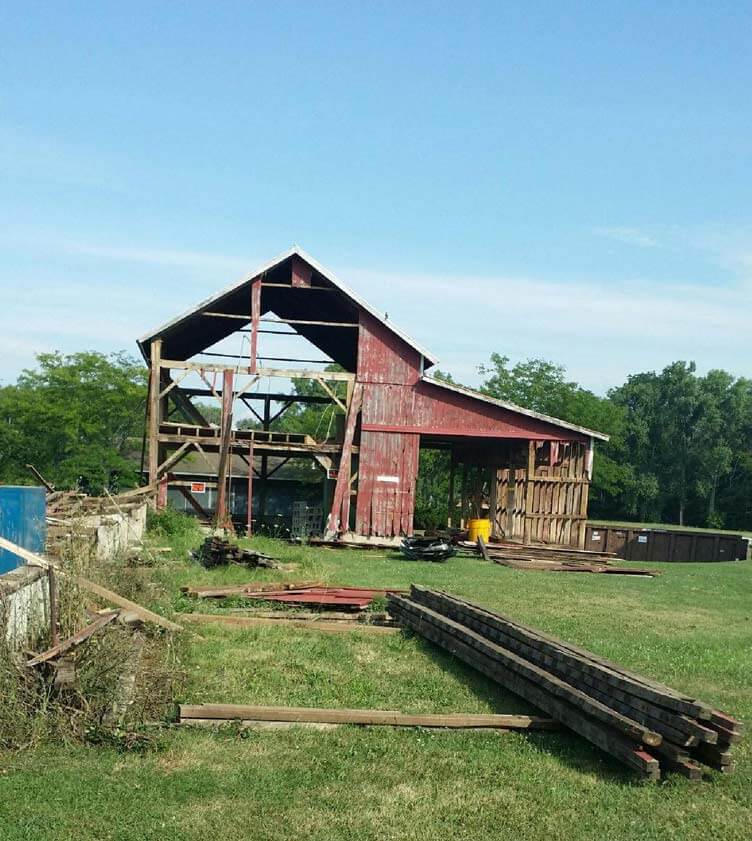 dilapidated red barn before being moved to new property and renovated