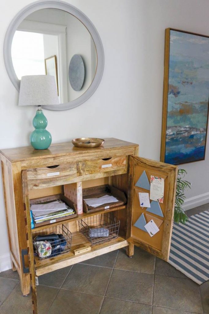 round mirror hung on a white wall above a brown repurposed wood cabinet 