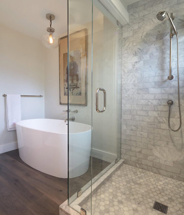 A bathroom with wood floors and light gray tile.