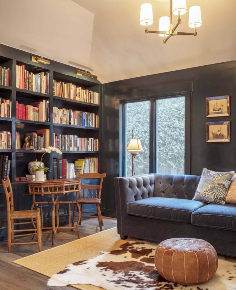 A functional room with bookshelves, a blue couch, and a cowhide rug.