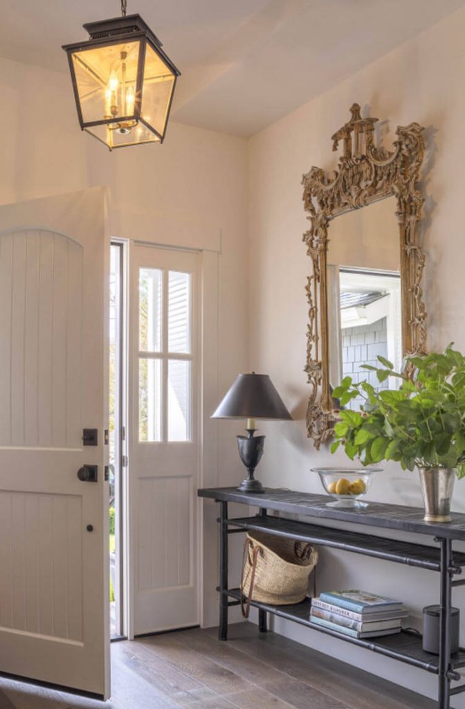 A front door and table with an ornate mirror.