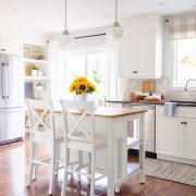 Clutter-free decor in a white modern farmhouse kitchen with high island, bar seating and sunflowers