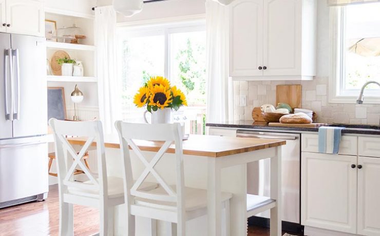 Clutter-free decor in a white modern farmhouse kitchen with high island, bar seating and sunflowers