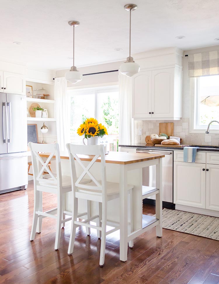 Clutter-free decor in a white modern farmhouse kitchen with high island, bar seating and sunflowers