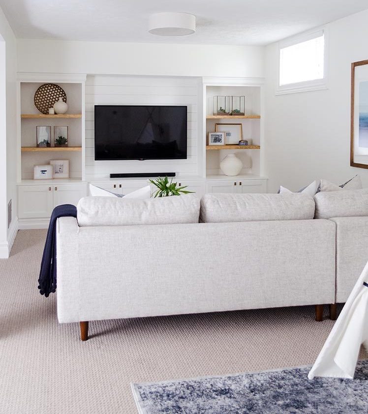 Clutter-free decor in a white family room with tv and built-in shelves