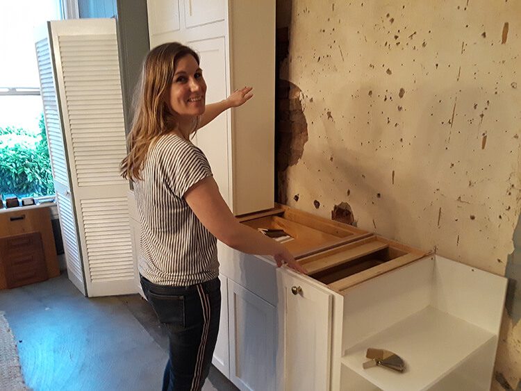 Holly discovering a brick wall with plaster behind kitchen cabients