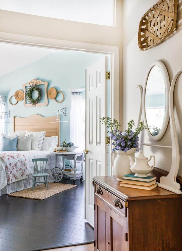 Hallway looking into blue bedroom, with vintage furniture, fresh flowers and soft textiles