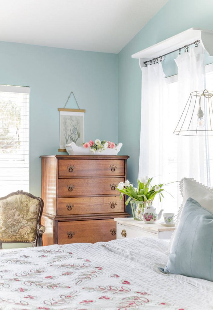 Bedroom with vintage wood dresser, hanging botanical print and fresh tulips.