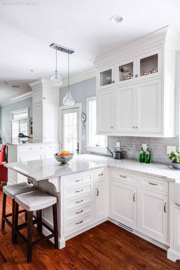 Simple white shaker cabinets and a marble countertop help create an elegant gray and white farmhouse kitchen.