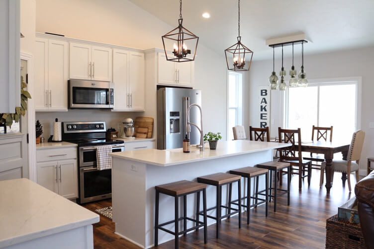 Two industrial style pendants hang over the island of a white kitchen.