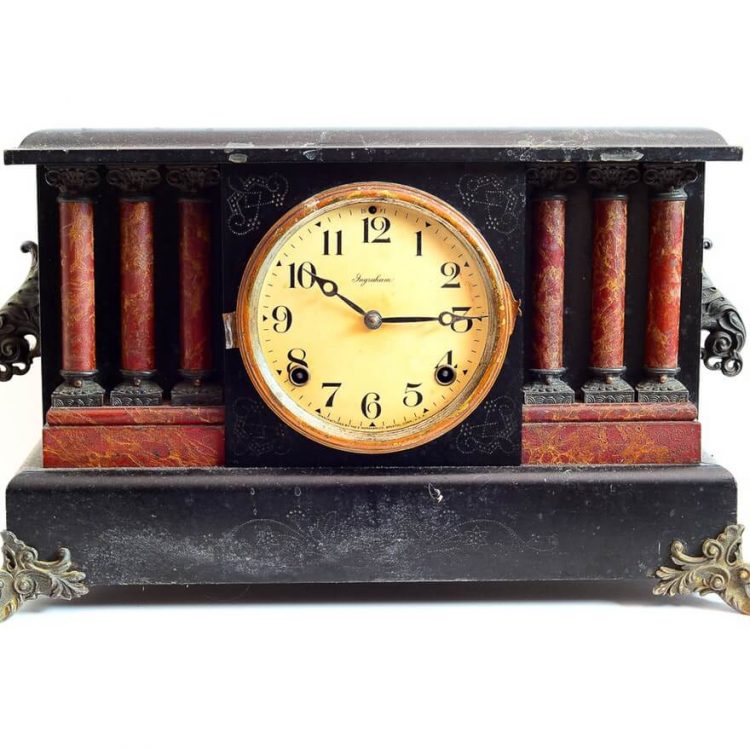 A vintage mantel clock with miniature auburn columns on either side of the clock face