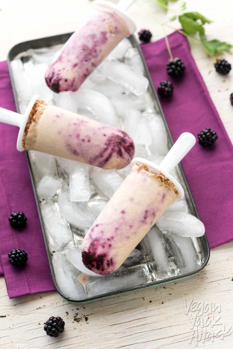 Three blackberry cheesecake pops with each popsicle resting on a bed of ice