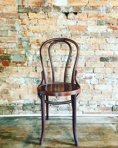 Bar style chair in front of brick wall.