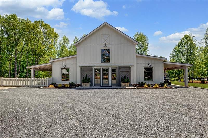 Glam party barn with white exterior and green shrubs