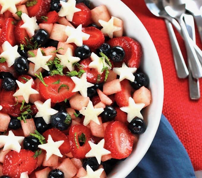A bowl of Fourth of July-colored fruit, complete with strawberries, blueberries, jicama, and a sprinkle of mint