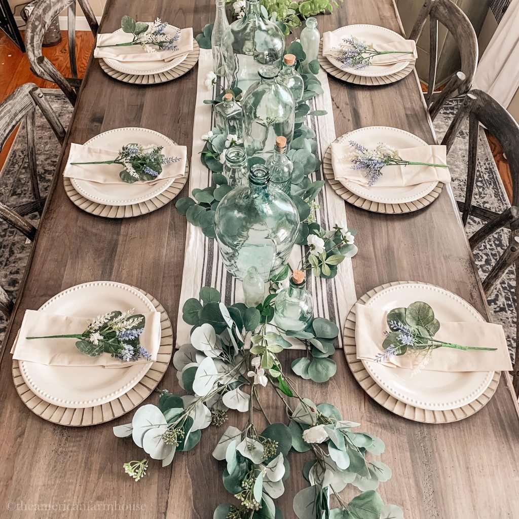 Beautiful upcycled tablescape includes aged bottles and silver dollar eucalyptus leaves