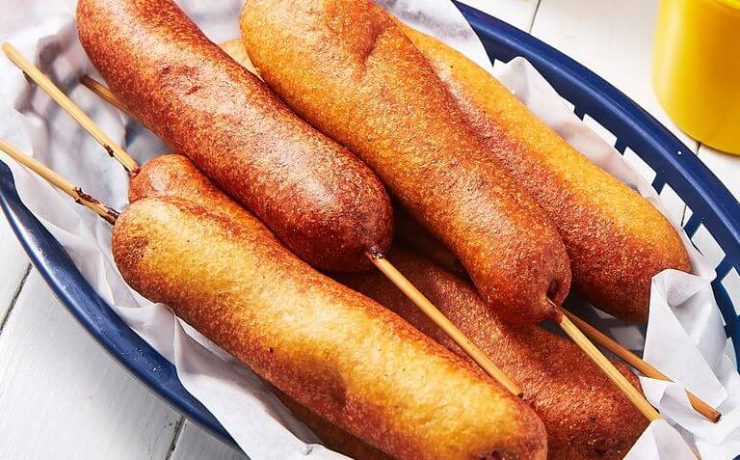A collection of Fourth of July corn dogs in a blue basket lined with paper