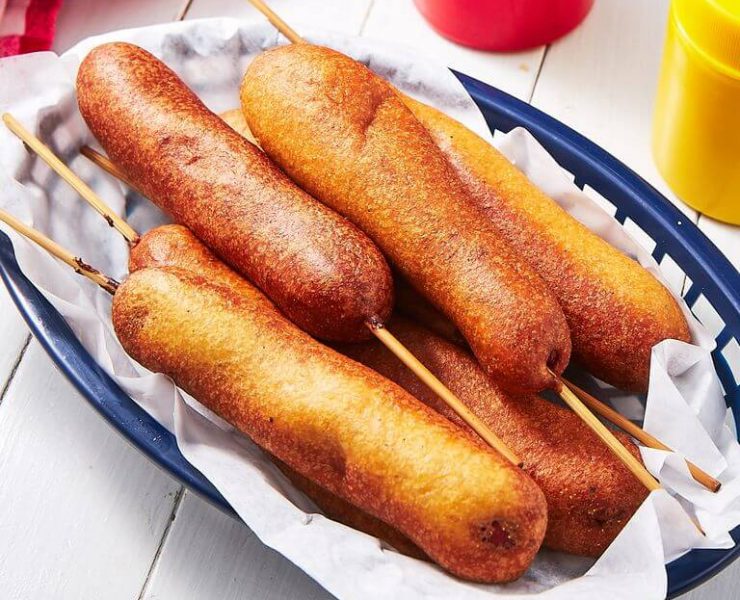 A collection of Fourth of July corn dogs in a blue basket lined with paper