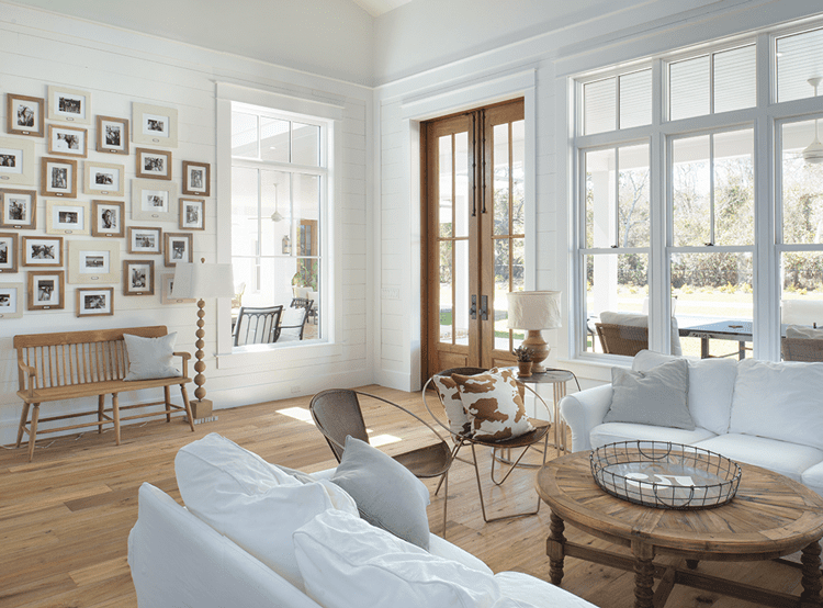 Living room with white couch, large windows, and gallery wall in wood paneled farmhouse