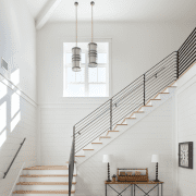 Dramatic staircase with a window and steel handrail in a wood paneled farmhouse