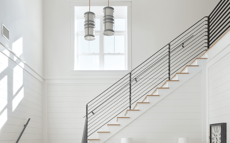 Dramatic staircase with a window and steel handrail in a wood paneled farmhouse