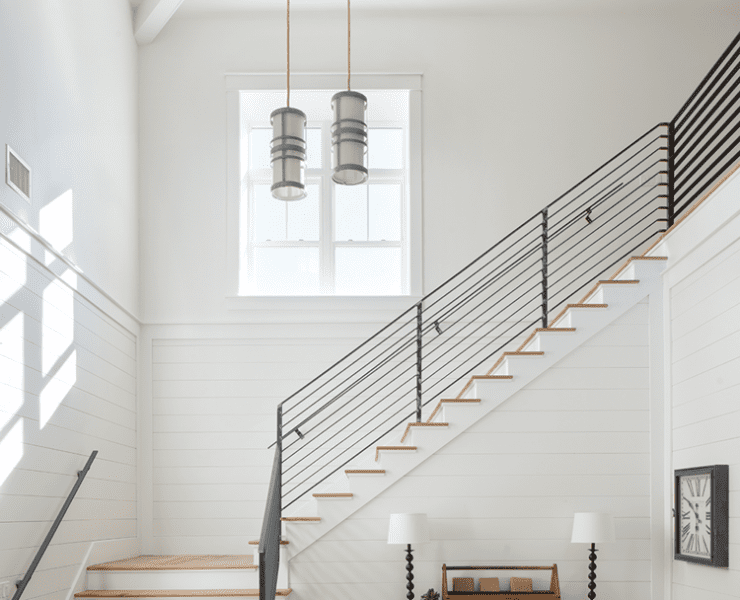 Dramatic staircase with a window and steel handrail in a wood paneled farmhouse