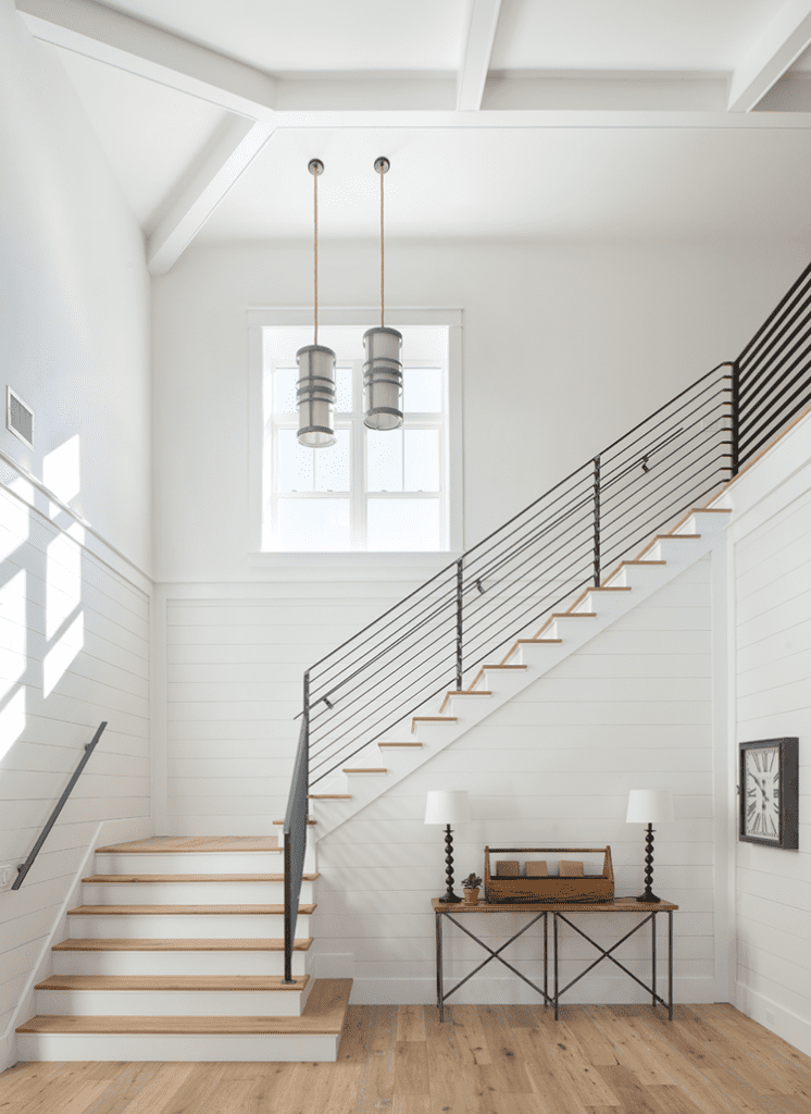 Dramatic staircase with a window and steel handrail in a wood paneled farmhouse