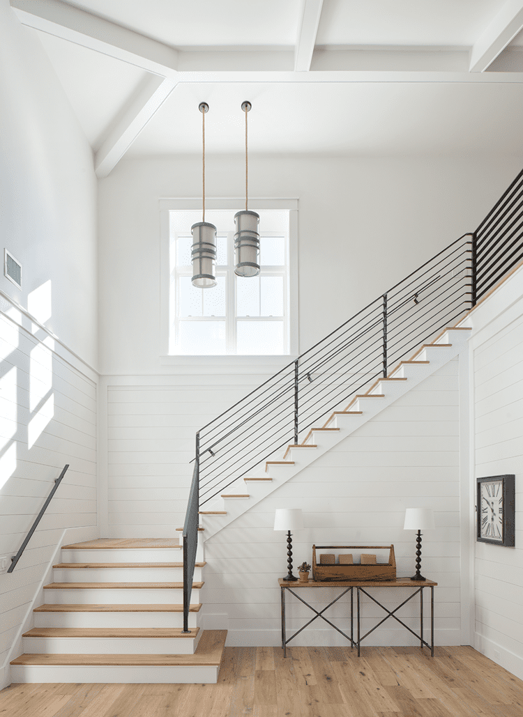 Dramatic staircase with a window and steel handrail in a wood paneled farmhouse