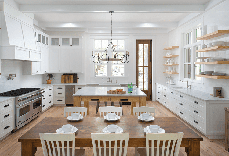 Large open kitchen with island and dining room table in wood paneled farmhouse
