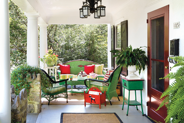 Open porch with columns and green furniture in historic farmhouse