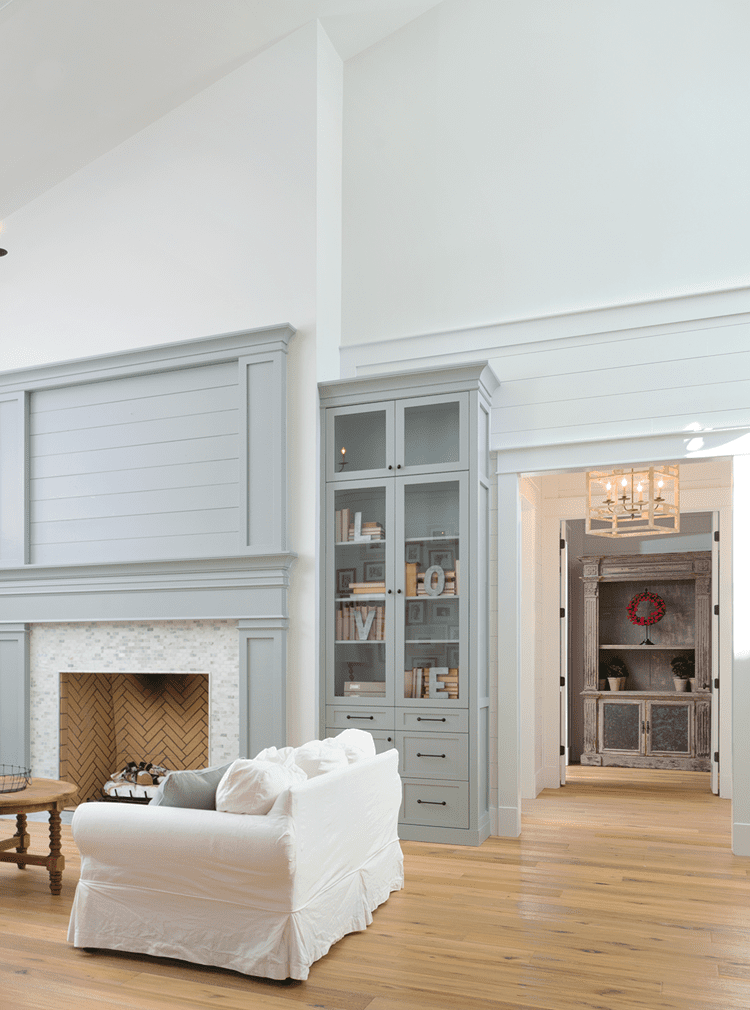 living room with high ceilings and gray fireplace in wood paneled farmhouse