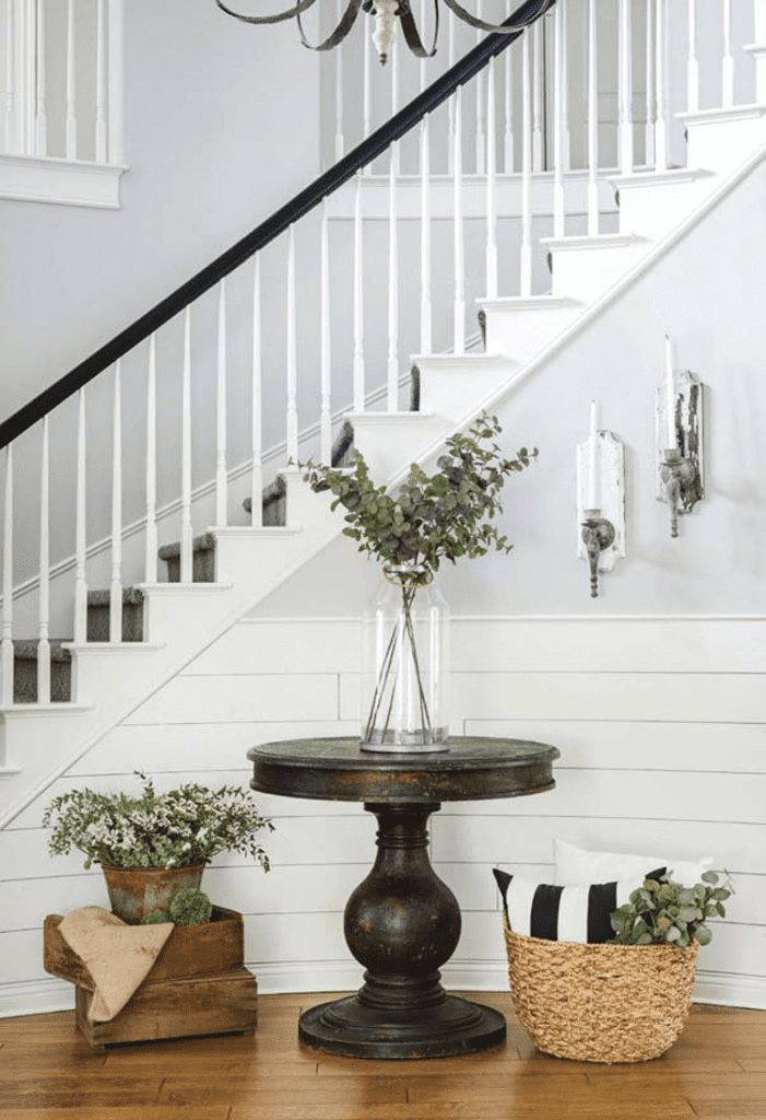 A foyer with a large staircase and banister in a custom farmhouse.