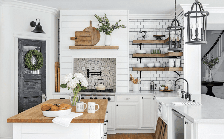 A kitchen with a butcher block counter, subway tile, and a marble countertop in a custom farmhouse