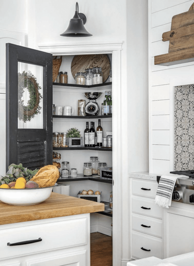 A kitchen with a black pantry door and butcher block counters in a custom farmhouse.