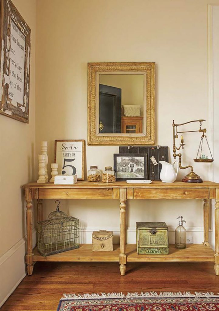 A vintage table from the 1900s in a renovated farmhouse, covered in picture frames and decor. 