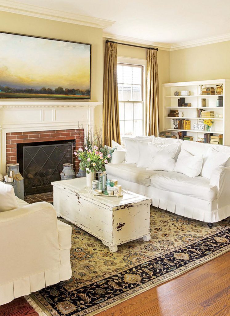 Renovated farmhouse living room with white couches, fireplace, and white coffee table