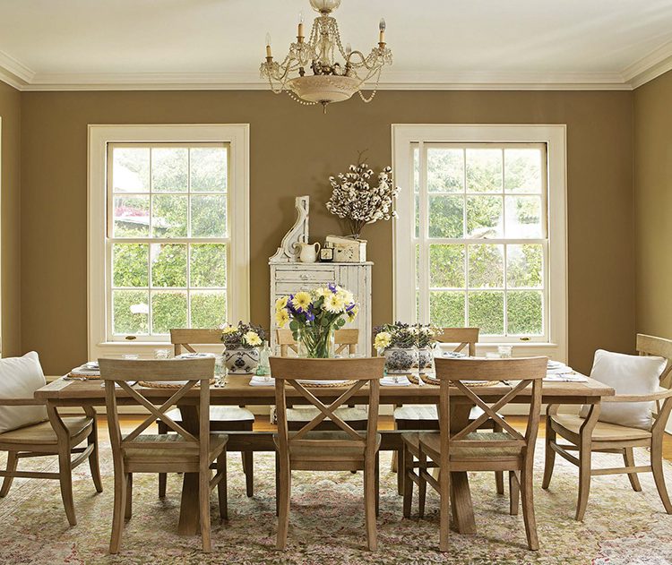 A renovated farmhouse dining room with a farmhouse table, chandelier, and windows.
