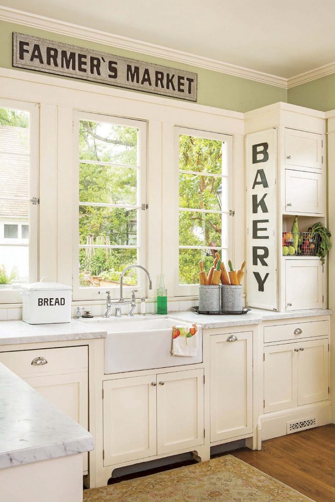 A white renovated farmhouse kitchen with a farmhouse sink and a large window.