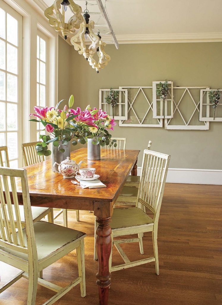 A renovated farmhouse dining room with a farmhouse table, DIY chandelier, and windows.