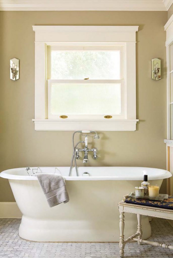 A renovated farmhouse master bathroom with a clawfoot tub and a window
