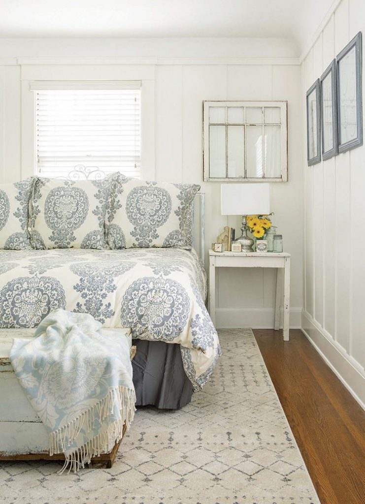 A renovated farmhouse guest bedroom with a paisley bedspread and a window.