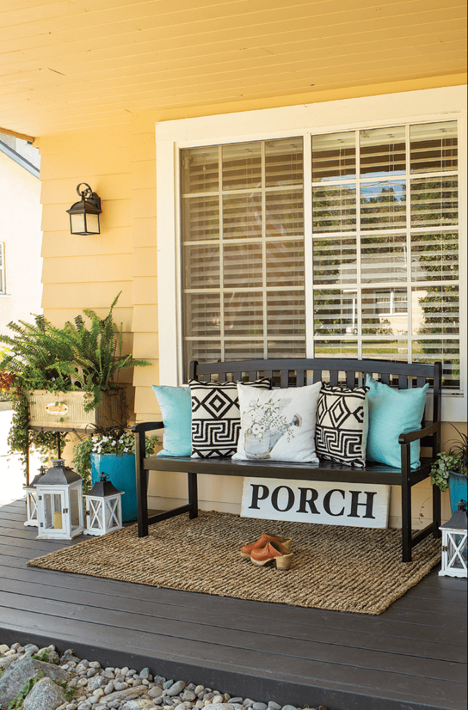Front porch with bench, throw pillows, plants, and farmhouse details.