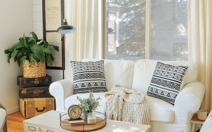 sarah joy blog's Seating area with white couch, plants, and throw pillows against a window