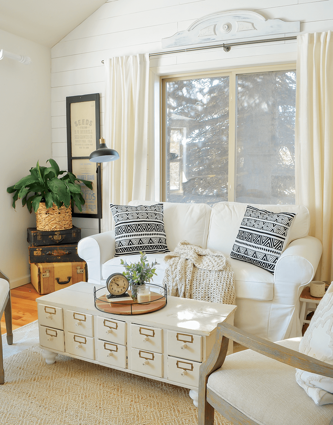 sarah joy blog's Seating area with white couch, plants, and throw pillows against a window