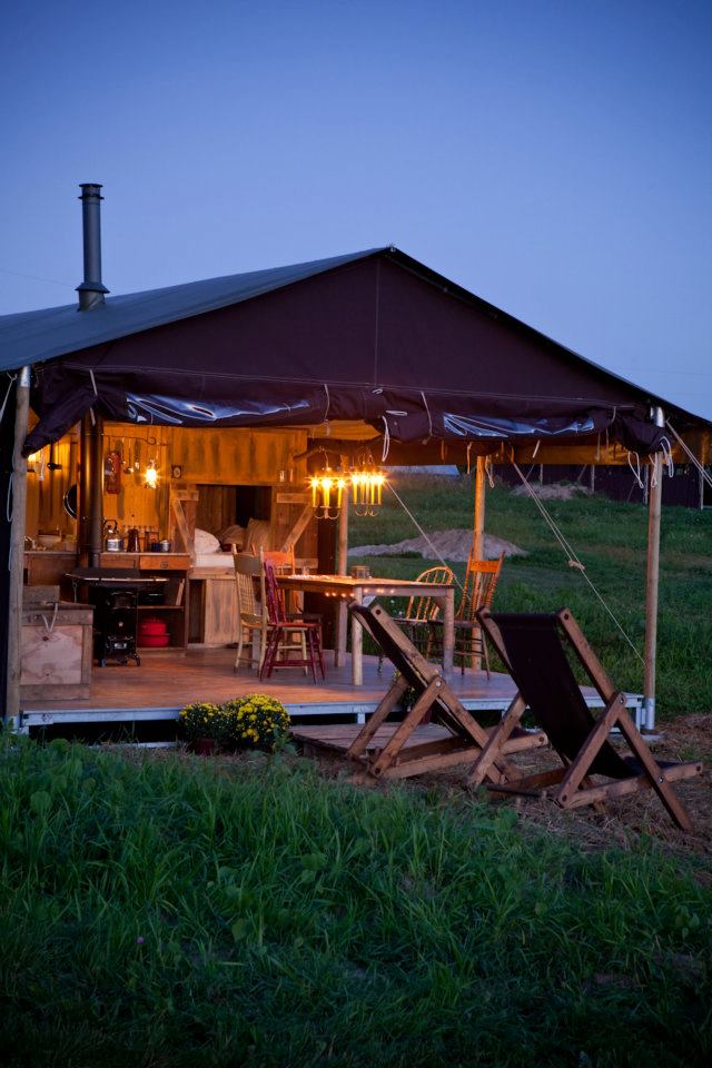 A tent with open flaps that open to deck and green grass.