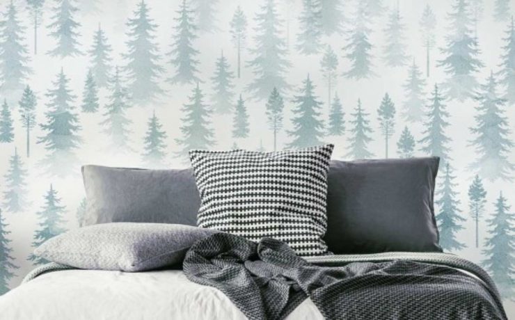 A wall mural made of many layers of tree stencils behind a bed.