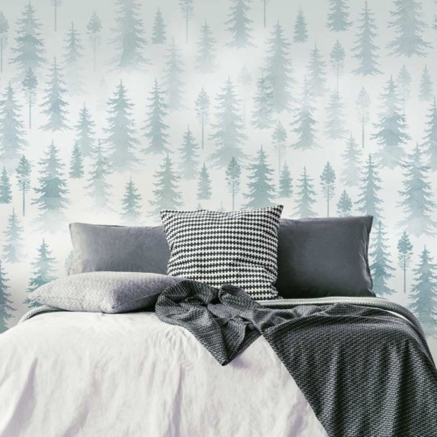 A wall mural made of many layers of tree stencils behind a bed.