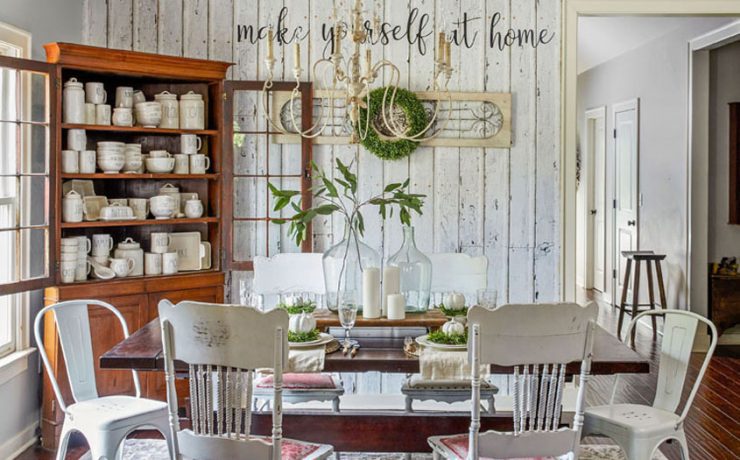 Dining room with white shiplap accent wall. Wooden cabinet displays many cream-colored dishes.